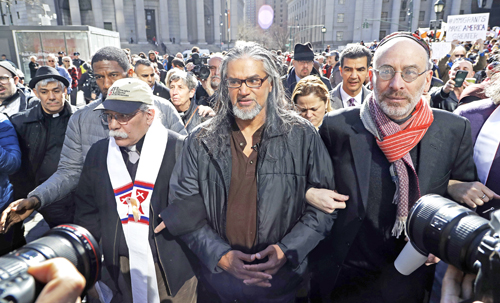 Ravi Ragbir, center, executive director of the New Sanctuary Coalition, walks with hundreds of supporters as he arrives for his annual check-in with Immigration and Customs Enforcement, Thursday, March 9, 2017, in New York.