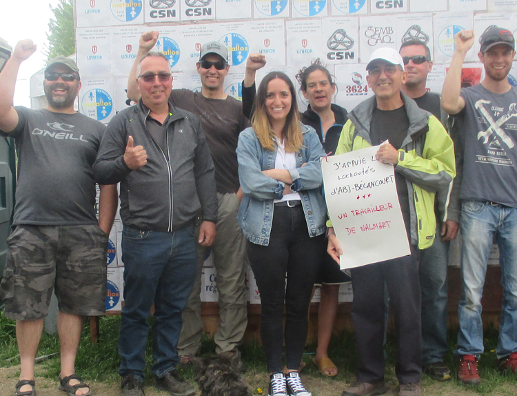 United Steelworkers members locked out by ABI Bécancour bosses in Quebec picket plant May 27, in front of solidarity wall. Walmart worker Michel Prairie holds poster of support.