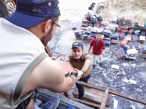 Voluntarios rescatan libros de la biblioteca de la Universidad de Mosul, la cual fue incendiada por el Estado Islámico.