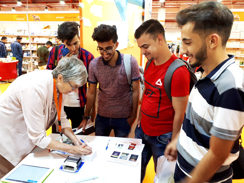 Munaf Ghanim, Mohammad Khalid Aswad, Safwan Al Madany y Saad Salim, voluntarios del festival de libros de Mosul visitan el stand de Pathfinder en la Feria Internacional del Libro de Erbil.