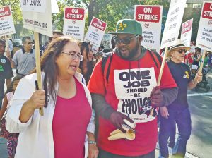 Laura Garza, Socialist Workers Party candidate for governor of California, walks hotel workers’ strike picket line outside Oakland Marriott City Center with striker Jason Russell Oct. 20.