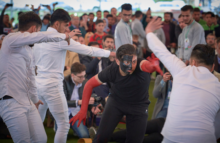 Mime performance by Mosul University students Nov. 30 acts out recent history. Dancers in white defeat Islamic State fighters in black, return a painting to view and a musician plays his flute to cheers of the crowd.