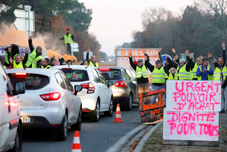 “Chalecos amarillos”, trabajadores de pueblos pequeños y del campo, ganan apoyo en Cissac-Medoc, Francia, 5 de diciembre. Cartel dice: Urgente. Poder adquisitivo. Dignidad para todos.