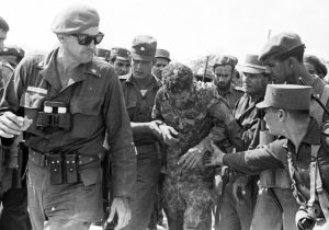 Above, José Ramón Fernández, left, leading Cuban forces against April 1961 U.S.-organized Bay of Pigs invasion. Behind him, revolutionary soldiers aid captured mercenary. Fernández carried out many responsibilities from training first militia battalions to helping transform education system. Left, José Ramón Machado Ventura, second secretary of Communist Party of Cuba, speaking at tribute to Fernández. Machado was medical doctor and combatant of Rebel Army during revolutionary war that overthrew Batista dictatorship in 1959.