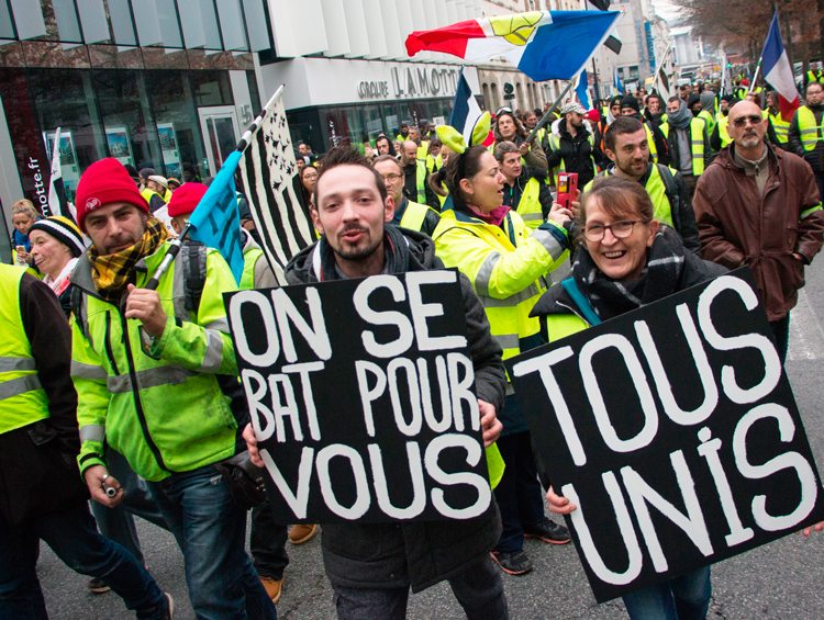 Yellow vest protesters march in Rennes, France, Dec. 29. “We fight for you,” sign on left says. Protesters continue pressing for further concessions from the French government.