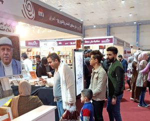 Thousands flocked to International Book Fair in Baghdad in February. At left is photo of Alaa Mashzoub, well-known Iraqi novelist who was murdered just days before start of book fair.