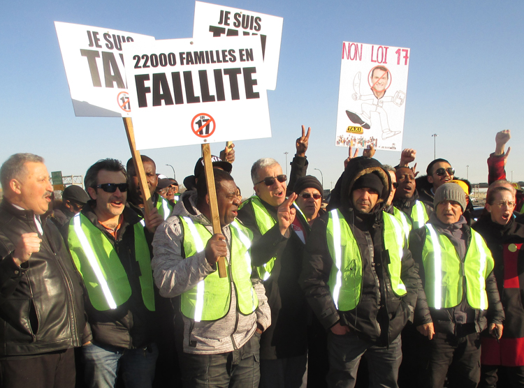 Montreal taxi drivers protest government deregulation bill April 5. Placard says, “22,000 families in bankruptcy.” Uber, taxi drivers need union to fight moves to pit them against each other.