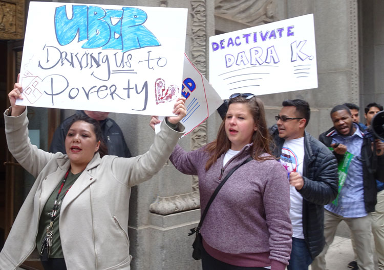 Uber, Lyft drivers picket City Hall in Chicago May 8. Sign refers to Dara Khosrow-shahi, Uber CEO. “We need to stand together,” Nnamdi Uwazie of Cab Drivers United told protesters.