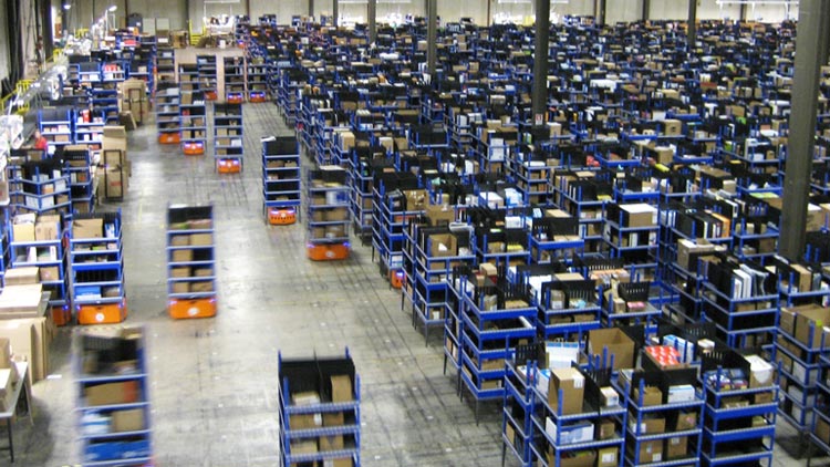 Robots cargados con mercancía corren por el almacén de Amazon, acelerando el ritmo de los empacadores. Los patrones dicen que cada segundo cuenta para las ganancias.