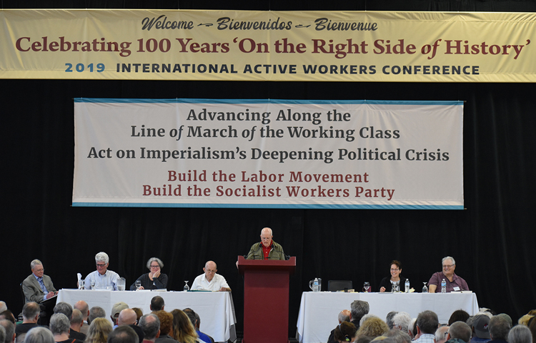 From left, John Studer, Dave Prince, Holly Harkness, Steve Clark, Jack Barnes (speaking), Mary-Alice Waters, Norton Sandler, at closing session of SWP conference June 15. Banners summarized continuity of Socialist Workers Party since 1919 founding of first communist party in U.S. and other Active Workers Conference themes.