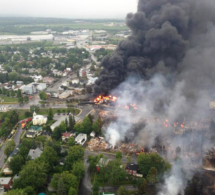 July 6, 2013, day of train derailment in Lac-Mégantic, Quebec, that killed 47 people. Upper left is Tafisa, largest particle board plant in North America. Plant depends on tracks that were rebuilt through center of town weeks after explosion and fire, while town center was razed.