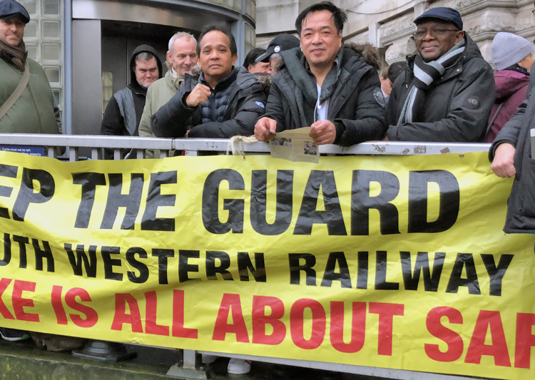 Picket at Waterloo station, London, during December strike against South Western Railway in defense of guard jobs, safety for rail workers and passengers. Fight by workers to get UK out of EU took place against backdrop of deepening capitalist crisis, growing disdain of Labour Party.