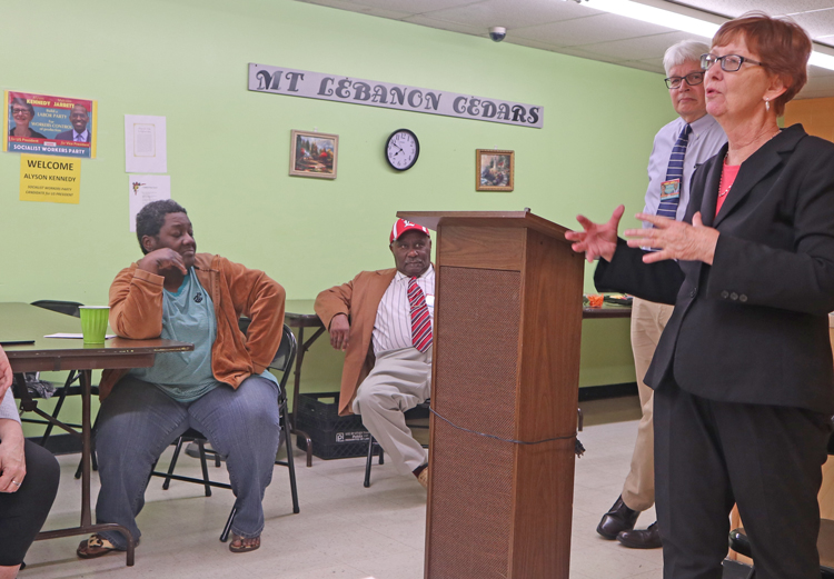 Socialist Workers Party presidential candidate Alyson Kennedy speaks to meeting at Louisville apartment complex Feb. 20, hosted by resident Lamont Anthony, seated behind podium.