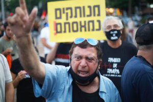 Tens of thousands protest July 11 in Tel Aviv, Israel, against government’s failure to deliver aid promised to workers classified as self-employed. Sign reads, “Out of touch! We’re fed up!”