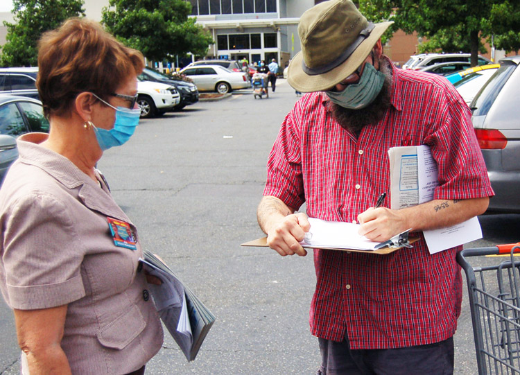 UPS worker Danel Griffin signs at Walmart parking lot to put SWP presidential candidate Alyson Kennedy, left, and running mate Malcolm Jarrett on the ballot in Washington state.