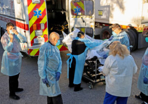 Hospital workers move bodies into refrigerated trailer in El Paso, Texas, Nov. 16. Shortage of beds, staff, equipment in for-profit hospital system increases toll of coronavirus pandemic.