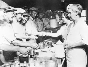 Teamsters Local 574 Women’s Auxiliary volunteers serve meals during 1934 Minneapolis strike. They also treated wounded picketers in strike hospital, spoke widely in region to win support.