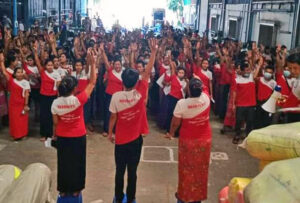Garment workers inside factory in Myanmar raise three finger salute, a symbol of defiance against military coup, Feb. 5. Mass protests and strikes exploded in face of military crackdown.