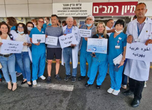 Trabajadores árabes y judíos en centro de salud Rambam en Haifa, 16 de mayo. Letreros en árabe y hebreo leen “judíos y árabes rehusan ser enemigos”. Esto es clave para lucha de clases.