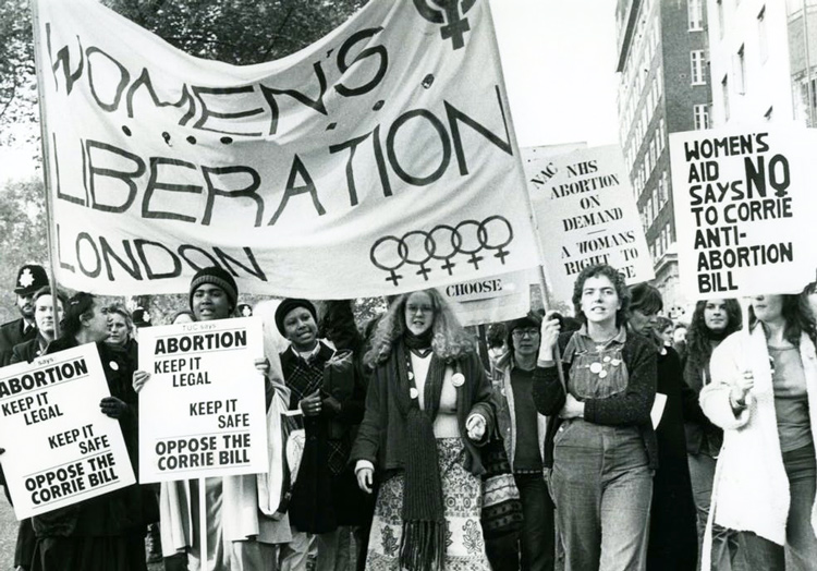 Maya Forstater, inset, won victory June 10 at London’s Employment Appeal Tribunal after being dismissed from job for stating that biological sex is “real, important, immutable.” This is a precondition for battle to win women’s emancipation. Above, major women’s rights march in 1979 in London.