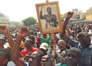 “The democratic and popular revolution needs a convinced people, not a conquered people,” says the sign above, quoting revolutionary leader Thomas Sankara under his photo. It’s carried in a June 29, 2013, protest against Blaise Compaore, who led the 1987 counterrevolution.