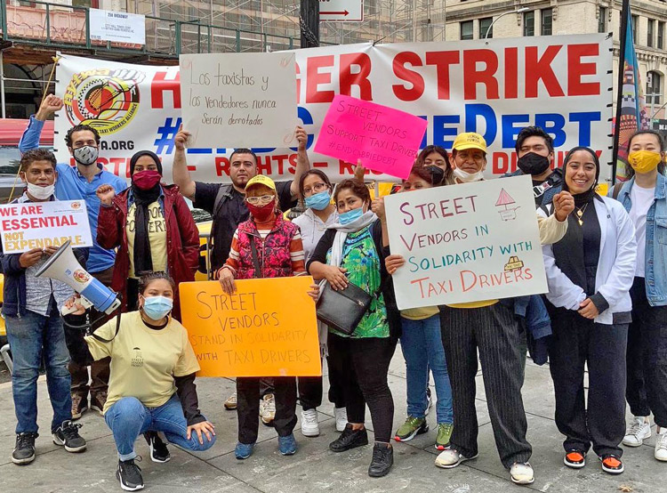 New York City cab drivers protesting at City Hall receive solidarity from street vendors Oct. 25. Banner says: “Hunger strike. End cabbie debt.” Medallions drove workers into debt.
