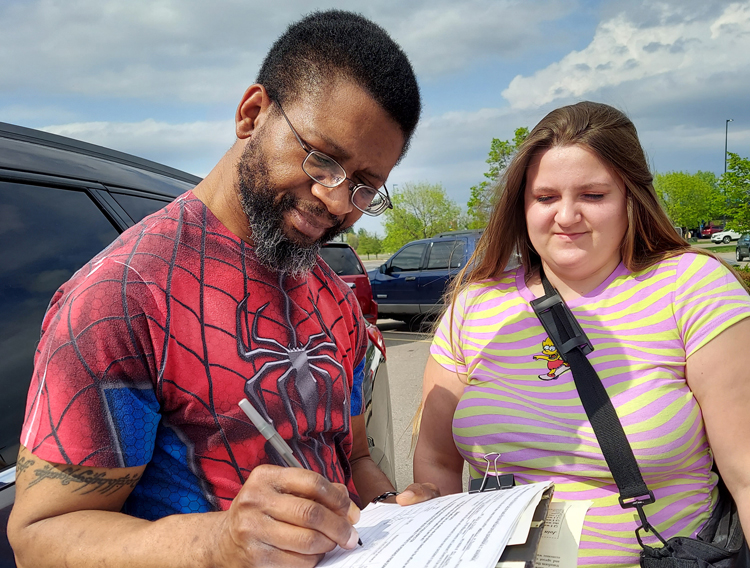 Michael Norville, left, signs petition to put SWP candidates on Minnesota ballot May 19 after discussion with Danielle Snyder about the party’s support for workers’ rights and unions.