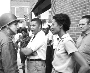 Col. Maurice Tawes fails to get civil rights leader Gloria Richardson to call off July 15, 1963, picket of segregated drug store in Cambridge, Maryland. Crime rate in the city plunged 75% during 1962-63 fight against Jim Crow segregation there. Richardson led the struggle, with union backing, in face of attacks from racist thugs and National Guard occupation of the city.