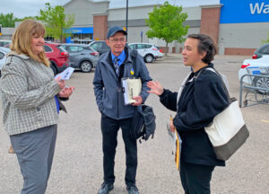 Reportera de Faribault Daily News de Minnesota entrevista a candidatos del PST Gabrielle Prosser y Kevin Dwire cuando hacían campaña en estacionamiento de Walmart el 26 de mayo.