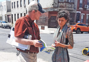 Chris Hoeppner, candidato del PST para el Congreso por Filadelfia, habla con Ammie Moralez sobre el programa del partido durante fiesta en su barrio, 26 de junio.