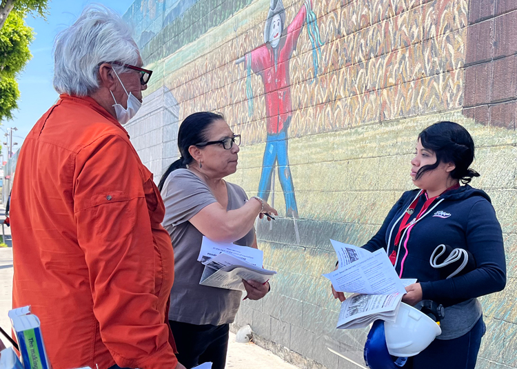 Eleanor García, center, Socialist Workers Party candidate for U.S. Senate from California, discusses impact of bosses closing Farmer John pork packinghouse with worker July 7.