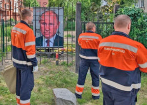 Gas company workers visit depiction of Russian President Vladimir Putin behind bars July 1 in Yekaterinburg, Russia’s fourth largest city. As officials gathered in front of media later, they didn’t remove Putin’s picture for fear it would be seen as insulting. It was covered over later.