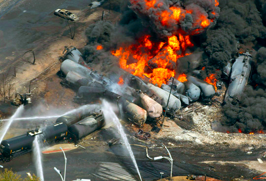 Derailed runaway oil tanker train killed 47 people in Lac-Megantic, Quebec, July 6, 2013. Rail bosses’ profit drive leads to long, fatiguing shift schedules; one-person “crews”; longer trains; and running dangerous cargo through urban areas, threatening more disasters.