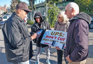 UPS worker Mark Rodriguez, left, renews Militant subscription at Teamsters protest Feb. 23 in San Francisco after discussion with Joel Britton, right, SWP candidate for California governor.