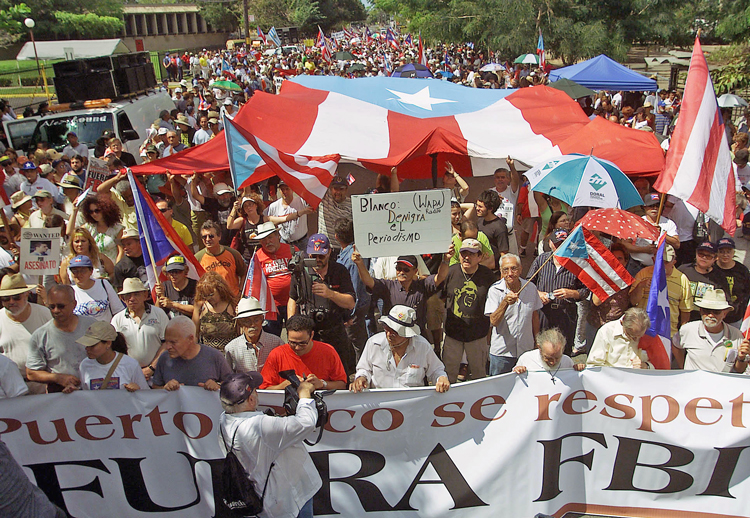 Miles marchan a edificio federal en San Juan, Puerto Rico, 26 de feb. de 2006, para protestar contra muerte de Filiberto Ojeda Ríos, dirigente de Macheteros, a manos del FBI y redadas a hogares de independentistas. En agosto, el FBI acosó a miembros de brigada que viajó a Cuba.