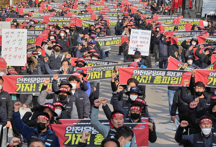 Hundreds of the 25,000 striking unionized truckers march in Uiwang, South Korea, Nov. 24, one of 16 nationwide rallies that day. South Korean government is trying to force them back to work. Signs demand a guaranteed minimum rate, safer working conditions.