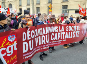 Paris demonstration, part of March 7 national protests against Macron government proposal to raise retirement age. CGT union banner says, “Decontaminate society of capitalist virus.”