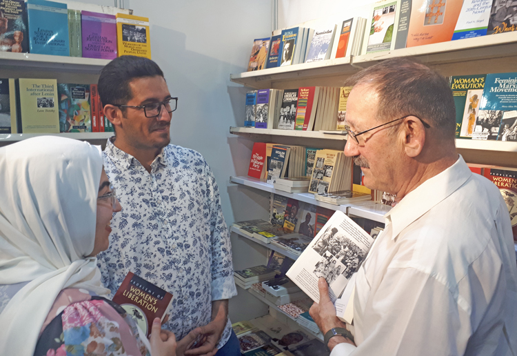 Voluntario Joe Young (der.), con visitantes a stand de Pathfinder en la feria del libro en Región de Kurdistán en Iraq. Participantes compraron 1,200 libros de líderes revolucionarios.