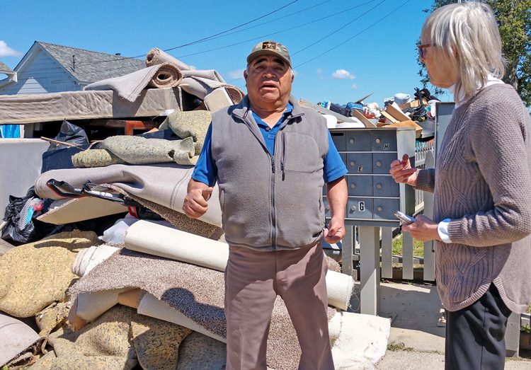Santiago Moreira, who has picked strawberries and other crops for 40 years, talks to SWP campaigner Betsey Stone beside belongings destroyed by flooding at his home in Pajaro, California.