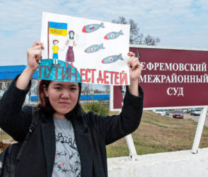 Yelena Tarbayeva holds sign, “Putin eats children” at court in Tula region south of Moscow April 6. She traveled 600 miles from St. Petersburg to support Alexei Moskalyov and his daughter, Maria, persecuted and separated for their anti-war views after Maria drew picture like this.