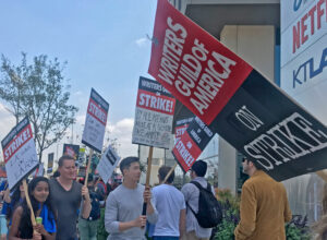 Hundreds of Writers Guild of America strikers and their supporters picket in front of Netflix in Los Angeles May 11. Writers are being forced to work longer hours for less pay.