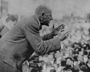At rally in Canton, Ohio, June 16, 1918, Eugene V. Debs speaks against first imperialist war and in support of Russian Revolution. U.S. rulers tossed aside Constitution’s protection of free speech for him and others, put him in prison. Debs was leader of rail workers, Socialist Party.