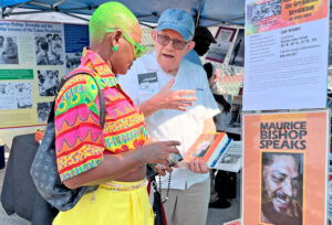 At Grenada Day Festival in Brooklyn Aug. 20 SWP leader Steve Clark shows Maurice Bishop Speaks to participant. Bishop led workers and farmers in 1979-83 Grenadian Revolution.
