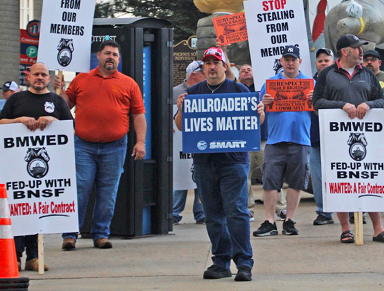 Rail workers picket North American Rail Shippers’ Kansas City conference, May 2022, during contract negotiations. Four rail workers have been killed on the job in the last seven weeks.