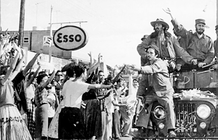 Fidel Castro and Camilo Cienfuegos, standing in jeep, right to left, during Freedom Caravan to Havana, Jan. 2-8, 1959. “They stopped me in the towns,” Castro said, “to speak with the people.” The revolution “had truly a+++complished something that was greater than ourselves.” 
