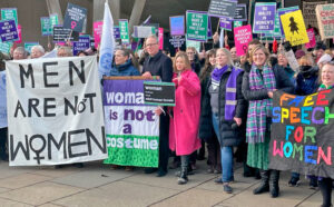 Protest at Scottish Parliament Feb. 9, 2023, over “transgender” men being put in women’s jail cells. Inset, J.K. Rowling faces “hate crime” charges over her support for ban on “all men — however they identify” in women’s spaces.