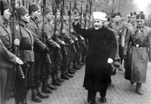 Amin al-Husseini, a forerunner of Hamas, salutes Bosnian Nazi SS units he organized during World War II to extend Hitler’s “Final Solution” to Mideast, Africa. He later led war to block Holocaust survivors from Palestine and destroy newly established Israel as a refuge for Jews.