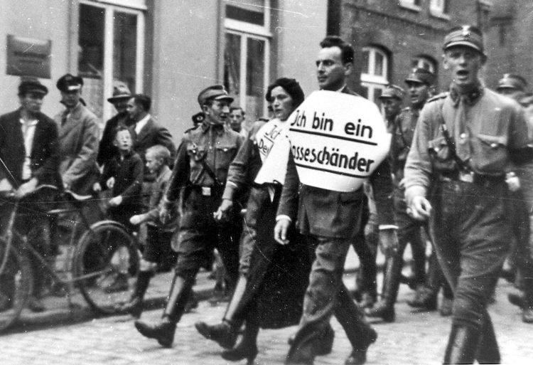 Julius Wolff, who was Jewish, and his non-Jewish fiancée, Christine Neumann, being paraded through Norden, Germany, by Nazi thugs in 1935. Wolff was forced to carry sign saying, “I am a race defiler.”