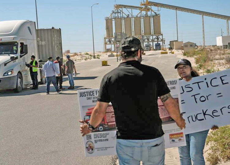 Members of Truckers Movement for Justice talk to truck drivers at Capital Sand mine July 1, in Monahans, Texas. They call for higher wages, pay for all hours on the job, better conditions.