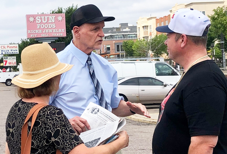 Dennis Richter (centro), candidato para vicepresidente de EUA, habla con Steven Lutchen, un camionero, frente a mercado en St. Paul, 4 de agosto. A Lutchen le gustó lo que escuchó y firmó la petición para poner a Rachele Fruit y a Richter en la boleta electoral en Minnesota.